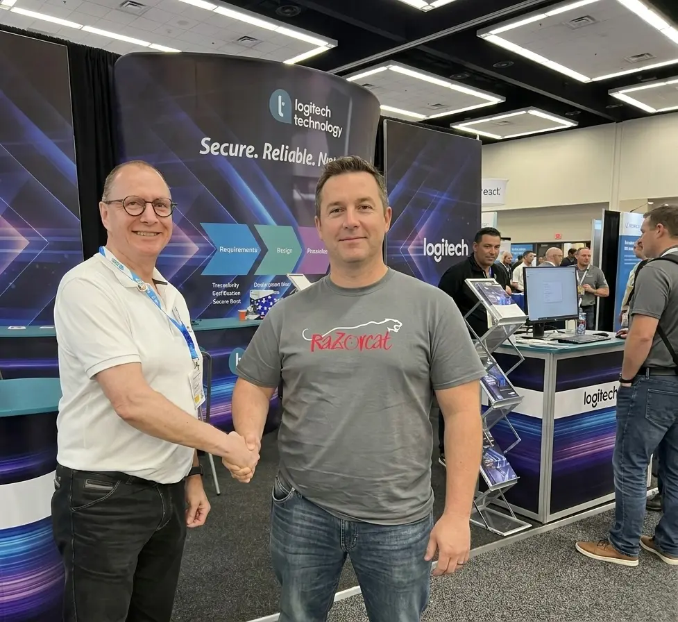 Logic Technology and Razorcat representatives shaking hands at an embedded systems trade show, announcing their new Benelux distribution partnership for the TESSY unit and integration testing solution
